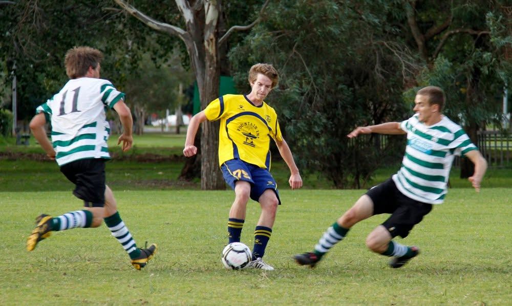 Zak on the ball against opposition in green hoops